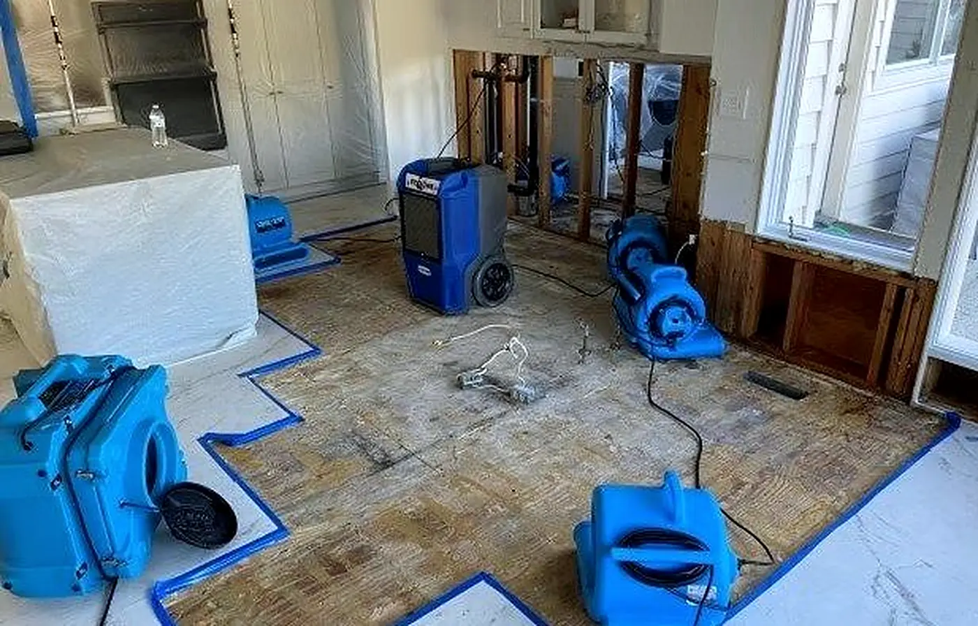 Air movers and dehumidifiers drying a water-damaged floor